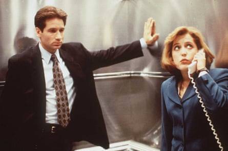 David Duchovny in The X-Files wearing a suit and tie, and Gillian Anderson wearing a navy jacket and holding a corded telephone