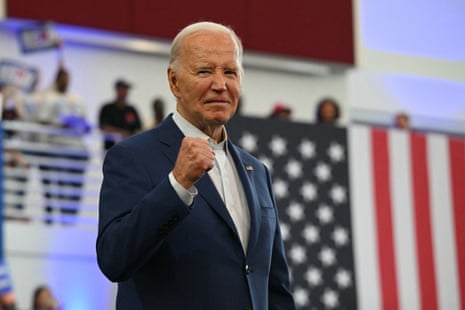 a man in a suit holds up a fist in front of an American flag