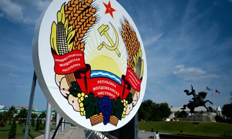 A woman walks past a huge coat of arms of Transnistria.