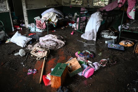 A view inside a cabin at Camp Mystic showing wet and muddy bedding and possessions.