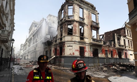 Strażacy pracują na zewnątrz zabytkowej rezydencji zniszczonej przez pożar podczas protestów w centrum Limy.