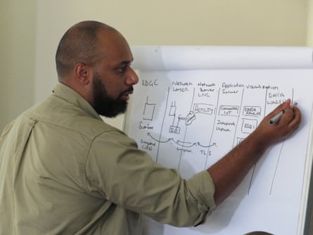 A man in a khaki shirt writes on a flip chart