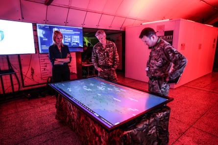 Military personnel look over a large digital map in the command centre