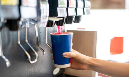 A person pouring a fizzy drink from a dispenser