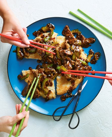 Three hands holding chopsticks hover over a plated noodle cake with shreds of beef and bitter melon on top