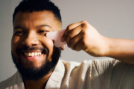 A man using rose quartz gua sha tool for face massage