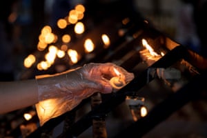 Wearing gloves for protection, a Christian lights a candle at a church in Metro Manila, the Philippines
