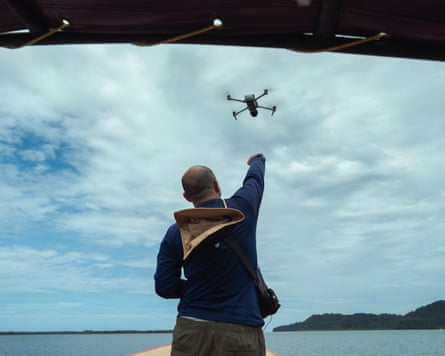 A man with his hand towards the sky, with a drone above him