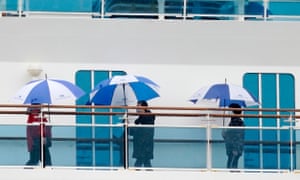 Passengers wearing masks walk on a deck of the Diamond Princess cruise ship docked in Yokohama.