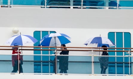 Passengers wearing masks walk on a deck of the Diamond Princess cruise ship docked in Yokohama.