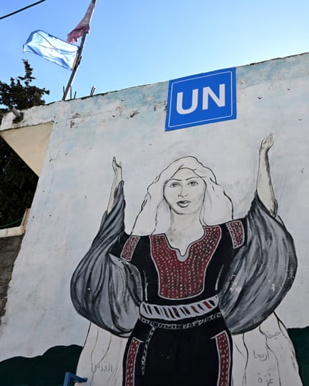 An image of a woman wearing flowing robes painted on the side of a building below the white UN logo on a blue background