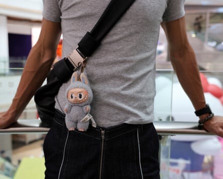 A person carries a bag with a Labubu doll attached
