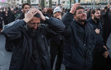 Men, including one with his hands on his head, gesture as they express their emotion