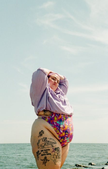 A fat tattooed sunbather at the ocean.