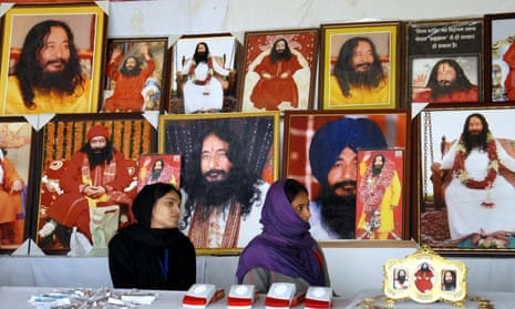 Indian followers of deceased guru Ashutosh Maharaj sit in front of posters bearing his image at a stall during a congregation at his ashram.