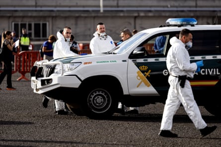People in hazmat suits near a Guardia Civil car.