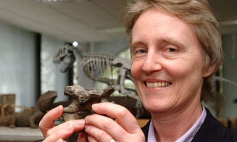 Angela Milner holding a small dinosaur tail vertebra in her office at the Natural History Museum.