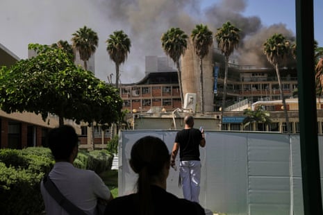 Smoke rises behind palm trees from a building