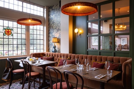 Plush sofas and in a pub dining room with tables laid under lamps and with window and mirror