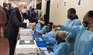 Governor Phil Murphy (Democrat of New Jersey) (L) fist bumps healthcare workers while touring a vaccination site with Vice President Kamala Harris at Essex County Community College in Newark on October 8.