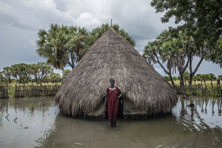 Bir kadın, Unity eyaleti Padeah'ta sel suları altında kalan aile kulübesinin önünde duruyor.  Ağustos 2020'de aile, Güney Sudan çevresindeki birkaç kuru araziden biri olan ve son yıllarda şiddetli sel baskınlarının gıda kıtlığını artırdığı Leer Kasabasına taşınmak zorunda kaldı.