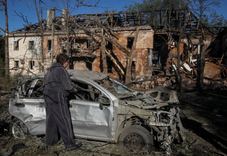 A resident inspects a destroyed car at the site of a Russian strike in Dnipro.