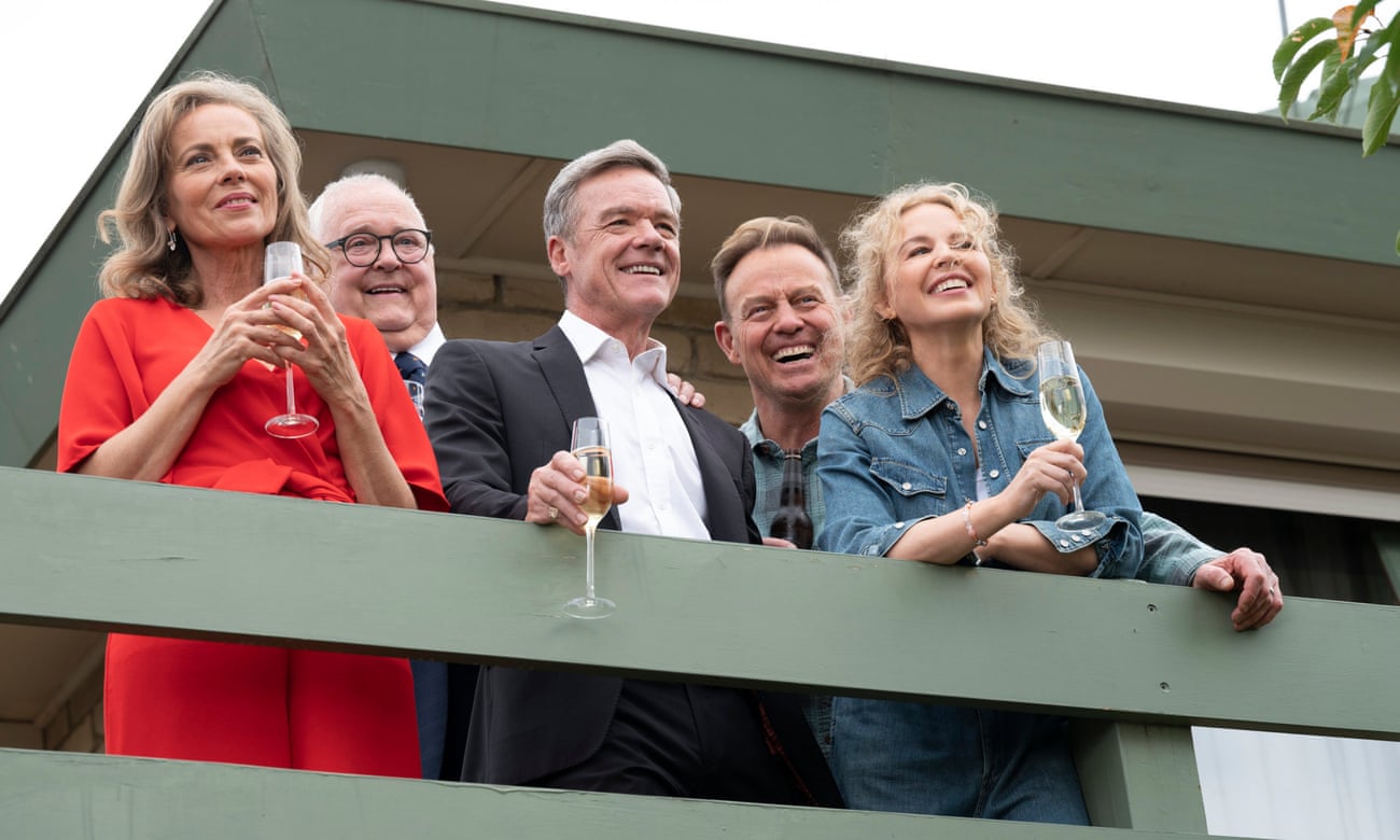 Jane (Annie Jones), Harold (Ian Smith), Paul (Stefan Dennis), Scott (Jason Donovan) and Charlene (Kylie Minogue) standing on a balcony drinking champagne in the final episode of Neighbours