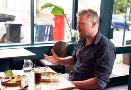 Miles gesturing and speaking while sat at the table.