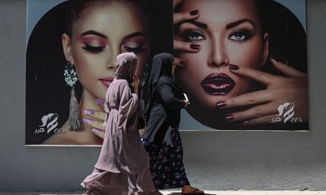 Women walk past a beauty parlour billboard in Kabul last week.