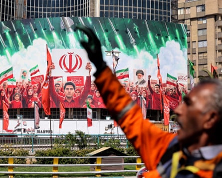 A man raises his hand in a defiant gesture near a large political banner in Tehran