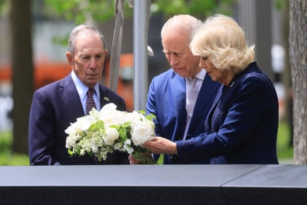 Two men in suits, and a woman in a blue suit jacket, with a bouquet of white flowers.