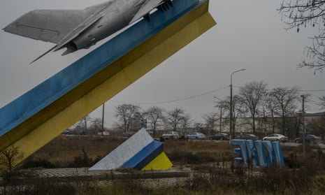 A line of cars near a Ukrainian monument leave Kherson on Saturday amid the civilian exodus