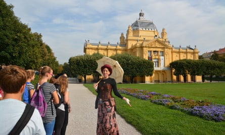 A costumed guide, in front of a grand civic building,
 on one of Secret Zagreb’s tours