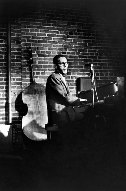 Black and white of Thomas Lehrer at piano with double bass in background