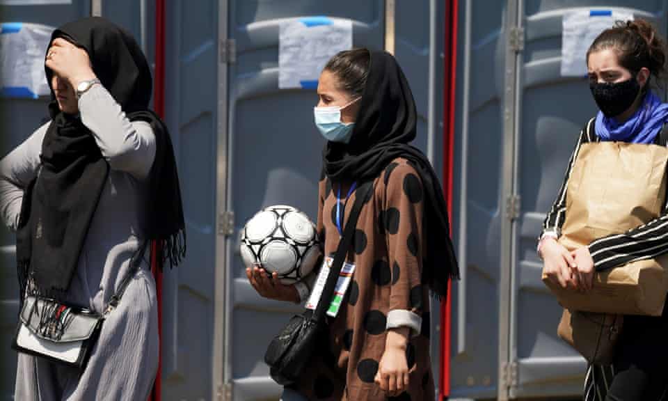 A woman holding a football and wearing a CAFA (Central Asian FA) lanyard waits in line at a refugee processing centre near Dulles airport, Washington DC.