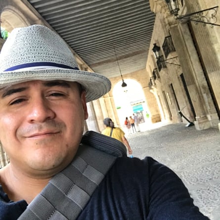 A man in a hat smiles in a hallway.