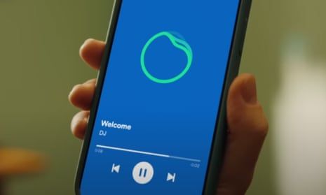 hand holds phone showing green circle on blue background, from Spotify's DJ service