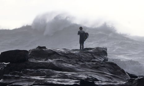 A surfer watches turbulent seas at Avoca Beach in Sydney, Australia