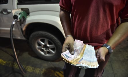 A petrol station attendant counts Venezuelan bolivar banknotes.