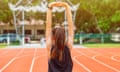 Back view of runner woman doing stretching and warming up her body before running in running track.<br>The benifit of stretching can increasing flexibility performance and reduce risk of injury.