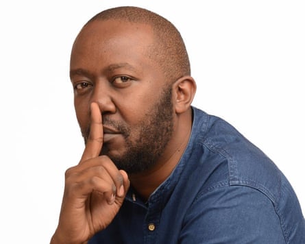Andrew Kibe sits with a finger on his lips in a 'shh' motion.