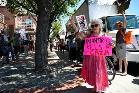 A woman holds a sign that says ‘Palantir kills in Gaza’
