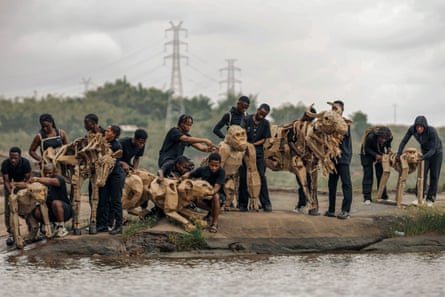 Lifesize herd of puppet animals begins climate action journey from Africa to Arctic Circle A team of puppeteers with lifesize puppets of a lion, baboon, monkey, zebra and wildebeest at the edge of a lake