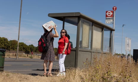 A woman protects herself from the sun at a bus stop