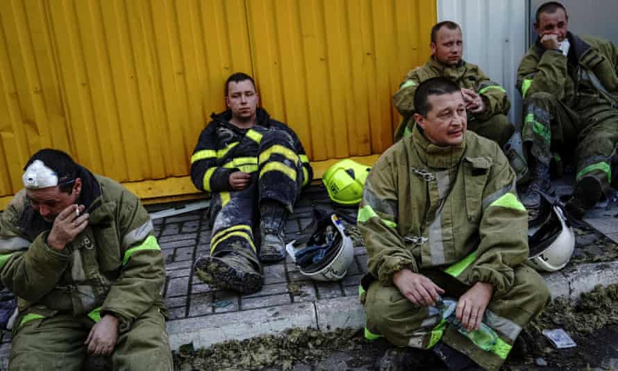Rescuers rest at a site of a shopping mall hit by a Russian missile strike.