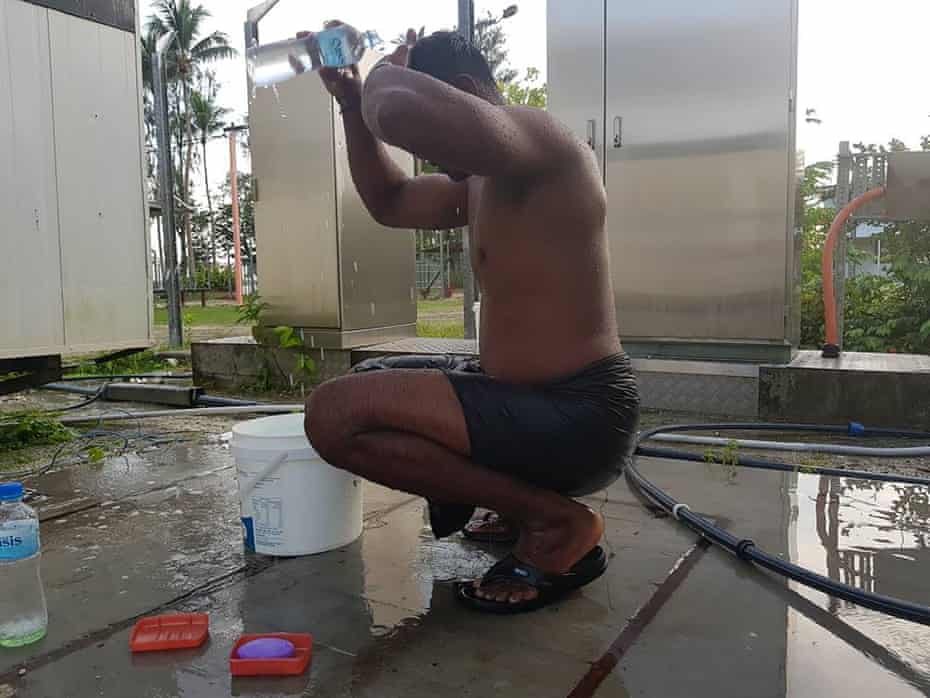 A refugee uses a bottle of water to wash himself at the Manus Island camp