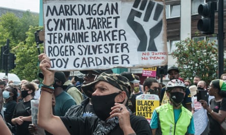 A protester holds a sign with Mark Duggan’s name on it to mark the 2020 anniversary of the riots.