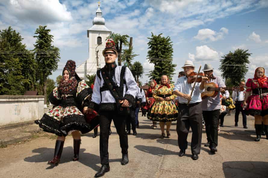 A bride and a groom with their guests and musicians leave a Romanian Orthodox church after a traditional wedding ceremony in the village of Tur.