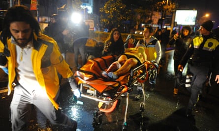 Paramedics carry an injured woman from the site of a mass shooting at an Istanbul nightclub.