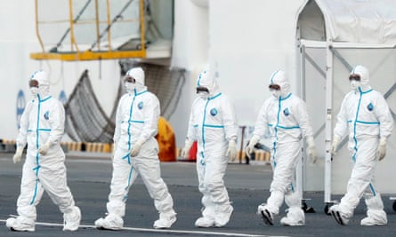 Workers wearing protective suits walk away from the cruise ship Diamond Princess